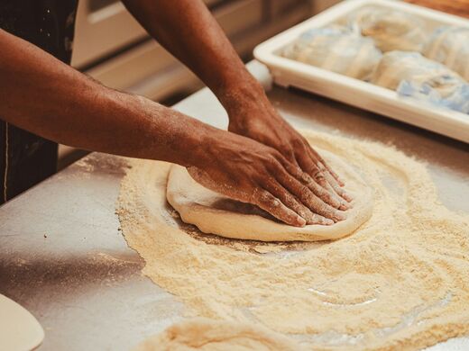 Mani che stendono l'impasto della pizza